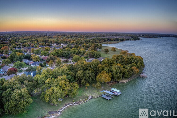 A beautiful aerial view of a coastal town with houses, trees, and boats at sunset.