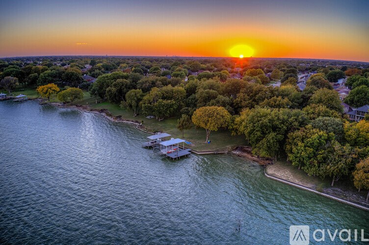 A sunset view of a body of water with a dock and trees.