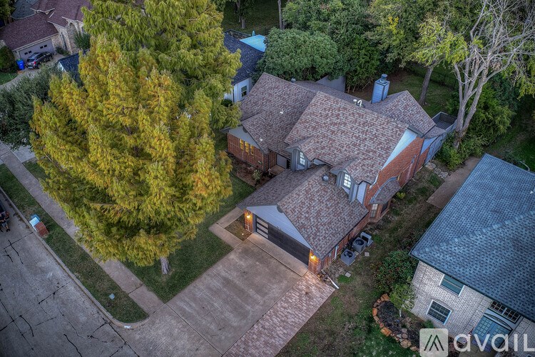 A house with a driveway and a tree in front of it.