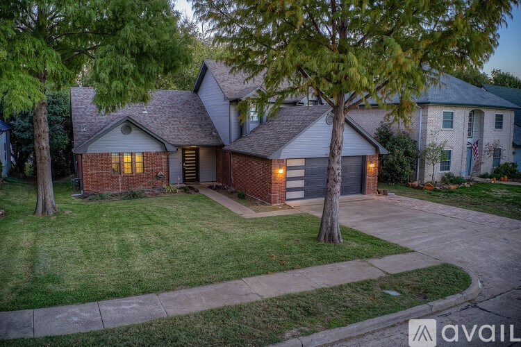 A house with a driveway and a tree in front of it.