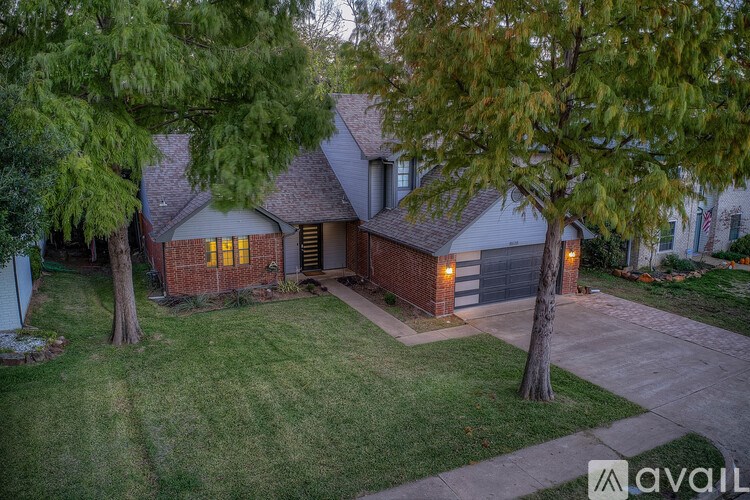 A house with a driveway and trees in front of it.