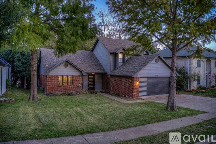 A house with a garage and a tree in front of it.