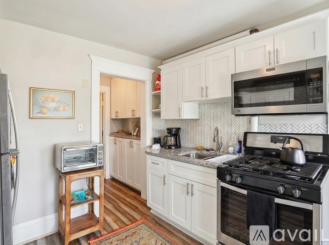 A kitchen with white cabinets and a patterned backsplash.