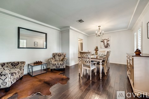 A living room with a cowhide rug and a chandelier.