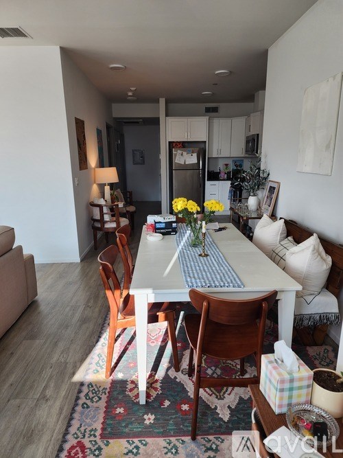 A dining room with a table set for two and a couch.