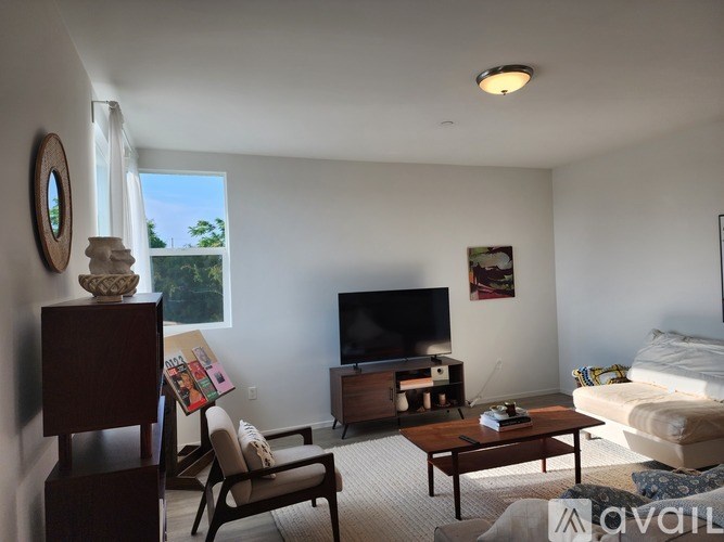 A living room with a television, a couch, a chair, a coffee table, and a mirror.