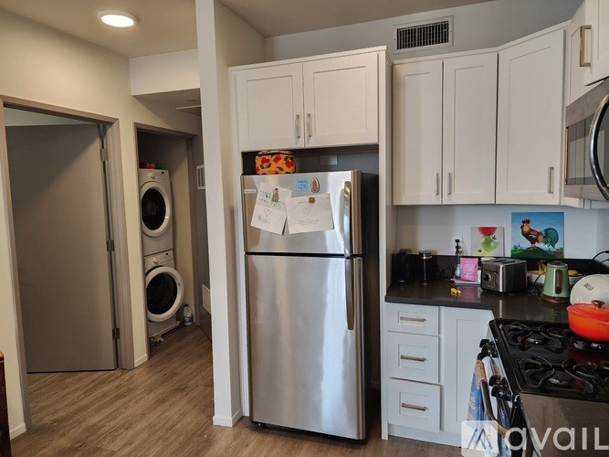 A kitchen with a stainless steel refrigerator and white cabinets.