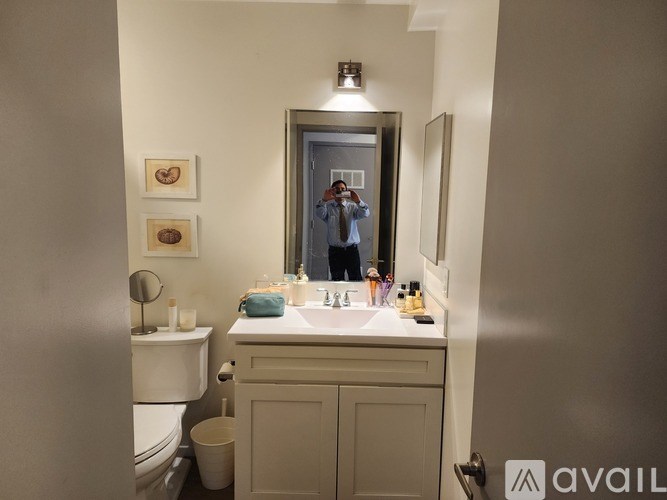 A bathroom with a toilet, sink, mirror, and a person taking a picture.
