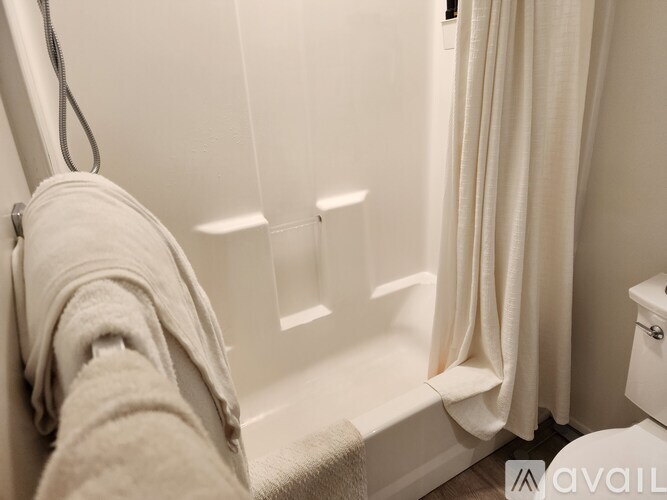 A white bathroom with a towel hanging on the tub.