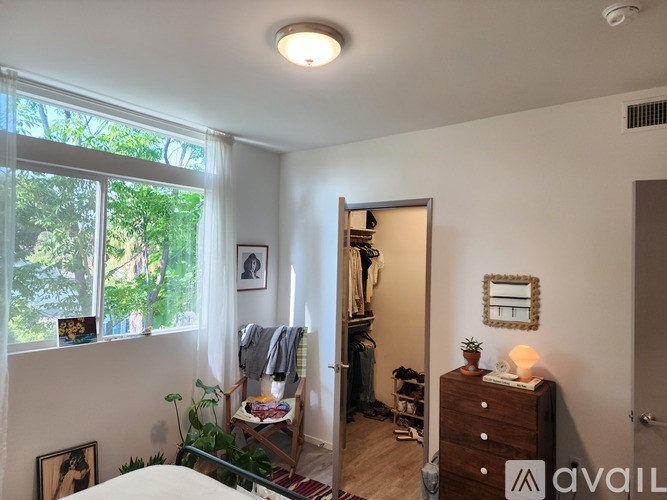 A bedroom with a bed, dresser, and a window with a view of trees.