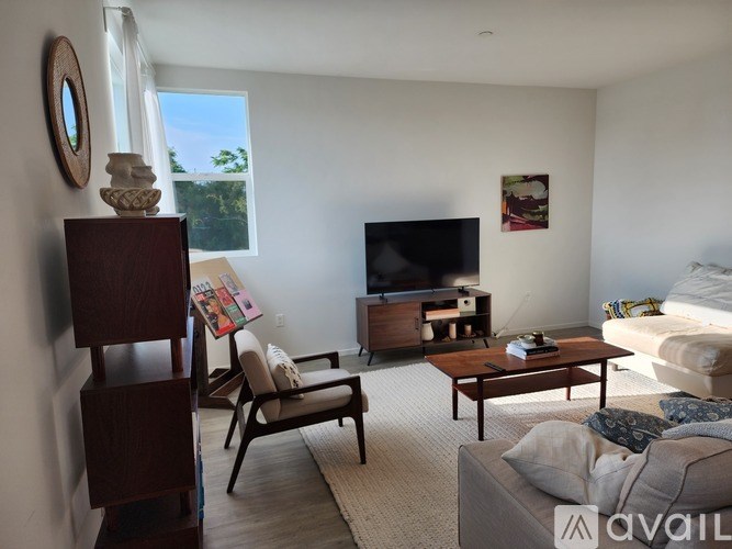 A living room with a television, a chair, a sofa, and a coffee table.