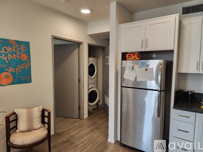 A kitchen with a fridge, cabinets and a chair.