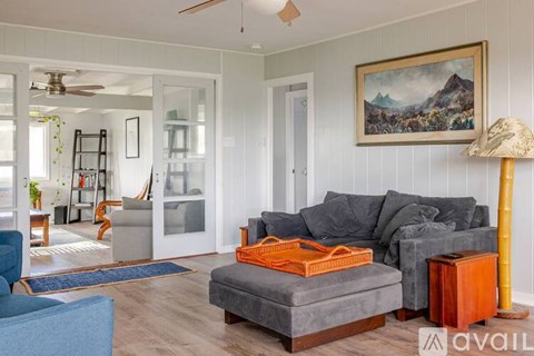 A living room with a grey couch and a painting on the wall.