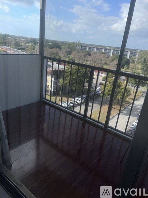 A balcony with a view of a parking lot and buildings.
