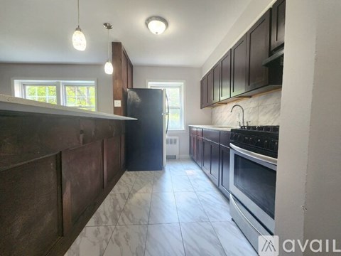 A kitchen with dark wood cabinets and a black refrigerator.