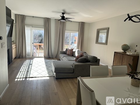 A living room with a grey couch and a white dining table.