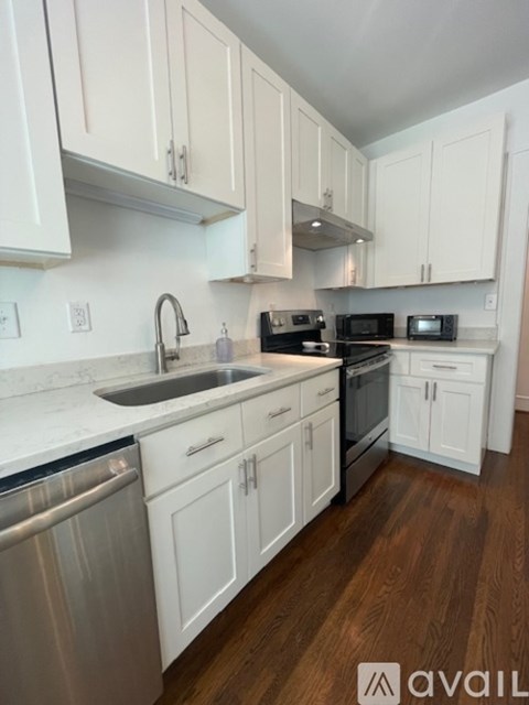 A kitchen with white cabinets and a wooden floor.