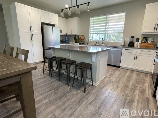 A kitchen with white cabinets and a wooden table.