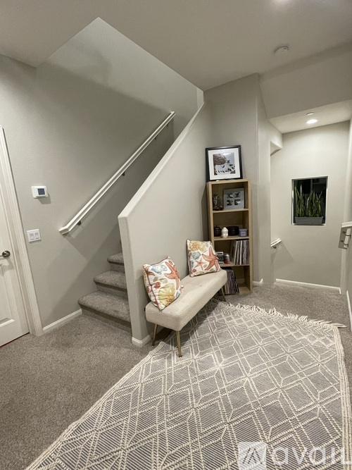 A living room with a grey carpet and a wooden bench.