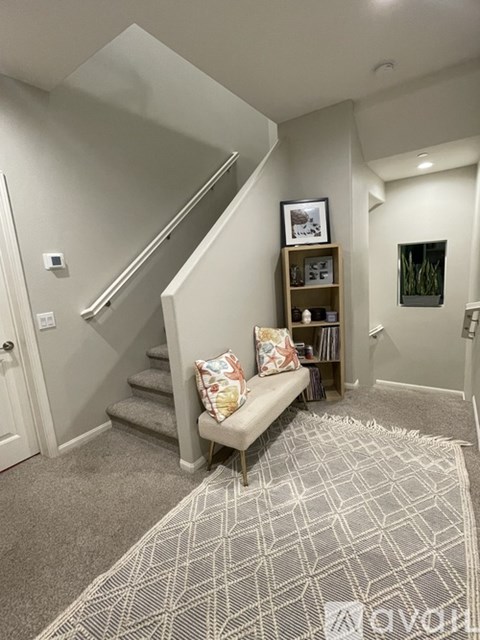 A living room with a grey carpet and a wooden bench.