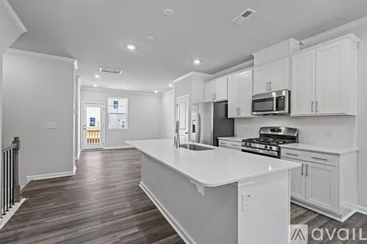 A modern kitchen with white cabinets and a wooden floor.