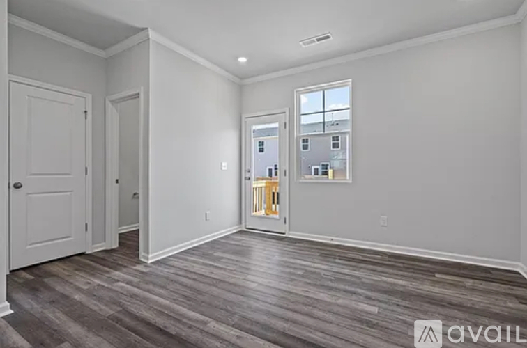 A spacious room with wooden floors and white walls.