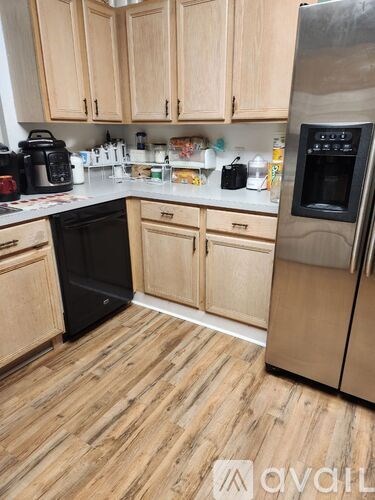 A kitchen with wooden cabinets and a black fridge.
