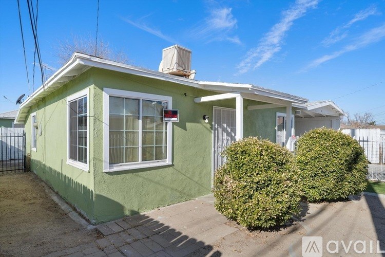 A green house with a white roof and a red sign on the front door.