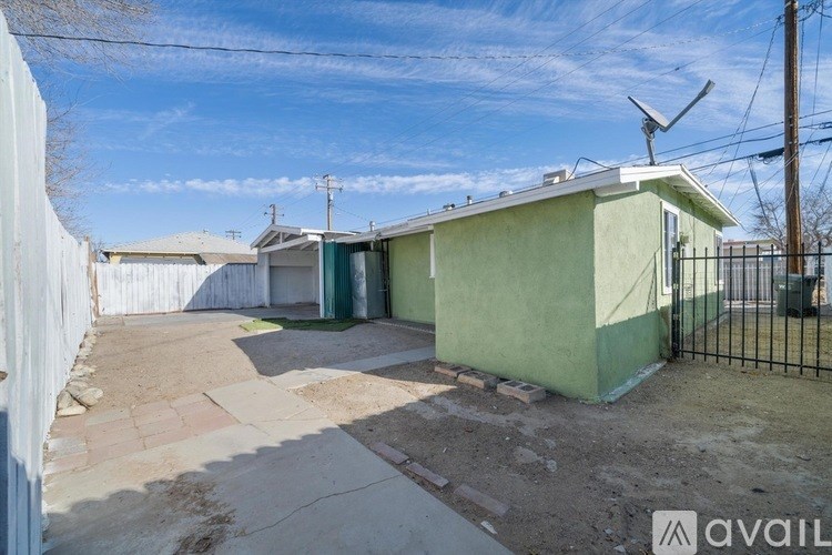 A green house with a white fence and a black gate.