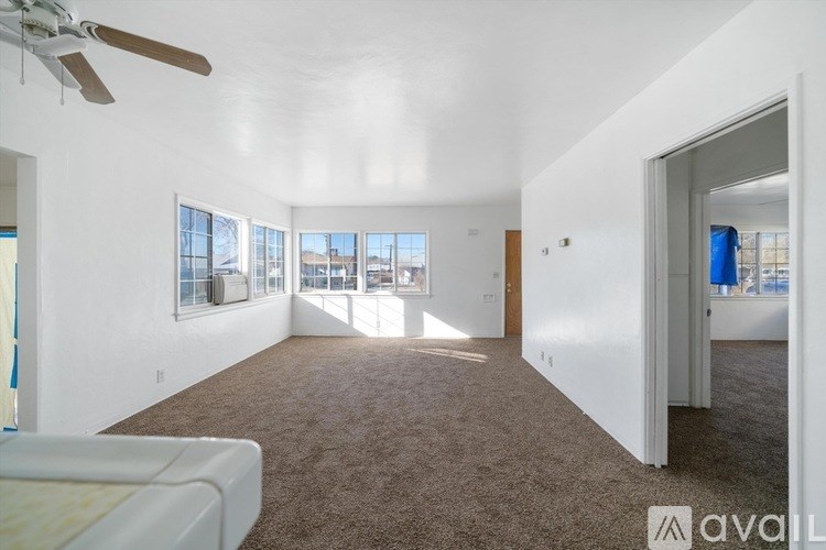 A spacious living room with a ceiling fan and large windows.