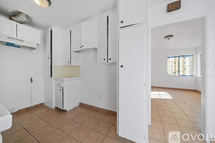 A kitchen with white cabinets and a white fridge.