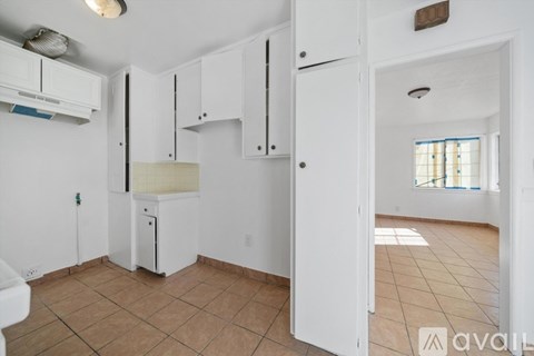 A kitchen with white cabinets and a white fridge.