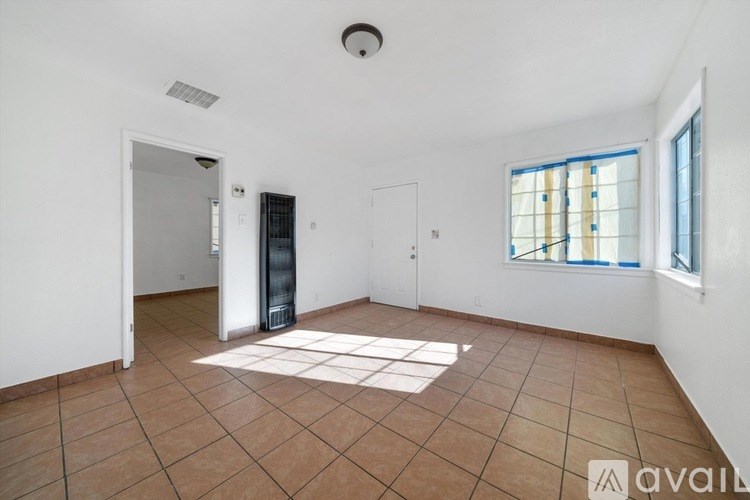 A room with a tiled floor and a window with blinds.