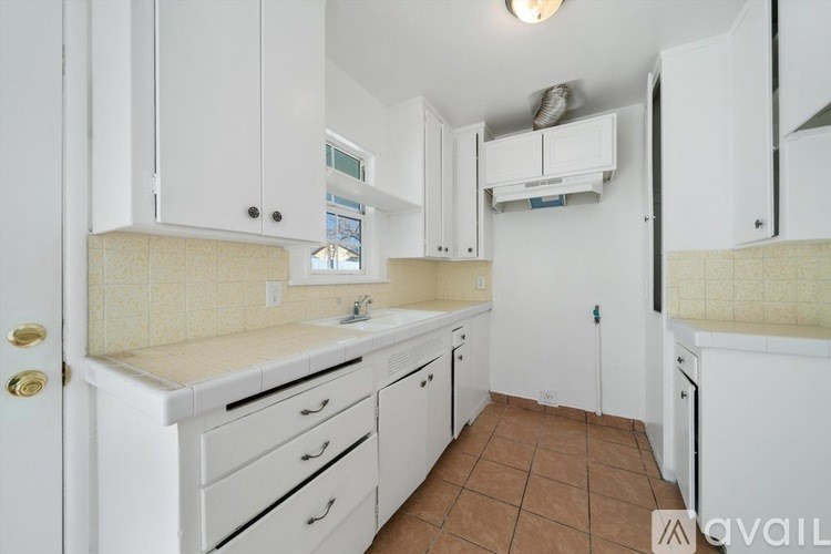 A kitchen with white cabinets and a tiled floor.