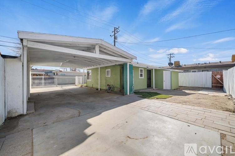 A large, open, and empty parking area with a white canopy and a green door.