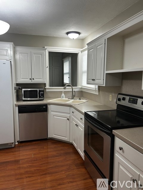 A kitchen with white cabinets and black countertops.