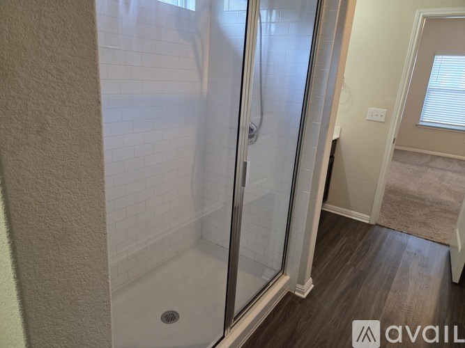 A bathroom with a walk-in shower and a wooden floor.