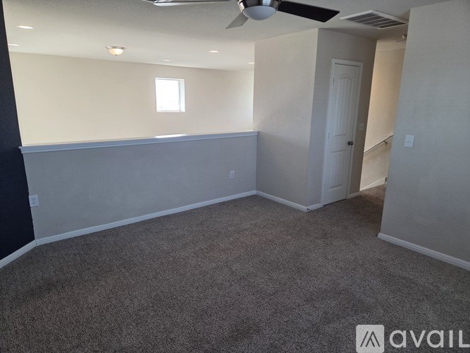 A room with a carpeted floor and a ceiling fan.