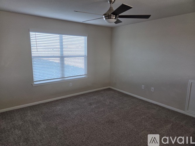 A room with a ceiling fan and a window with blinds.