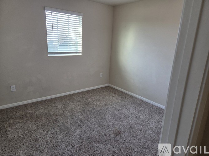 A room with a carpeted floor and a window with blinds.
