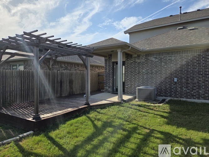 A backyard with a wooden deck and a pergola.