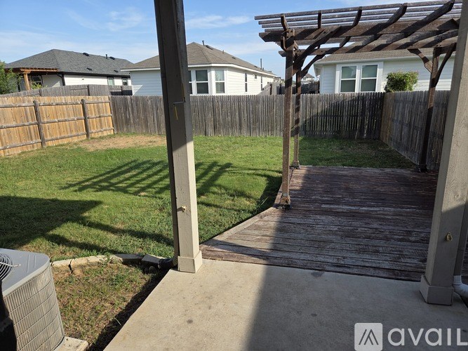 A backyard with a wooden deck and a pergola.