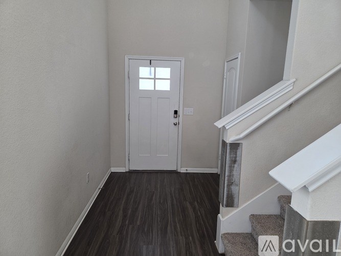 A white door is in the middle of a hallway with a staircase on the right.