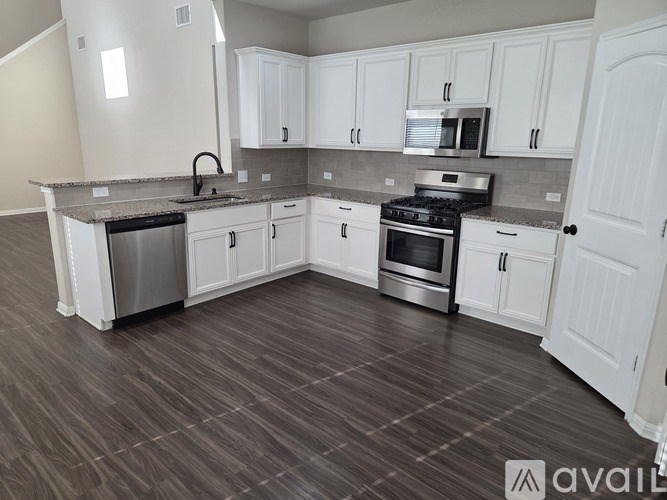 A kitchen with white cabinets and a wooden floor.