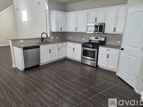 A kitchen with white cabinets and a wooden floor.
