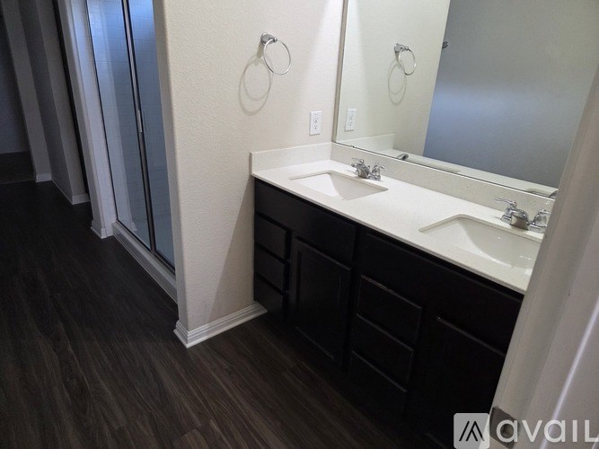 A bathroom with a sink, mirror, and a shower with a glass door.