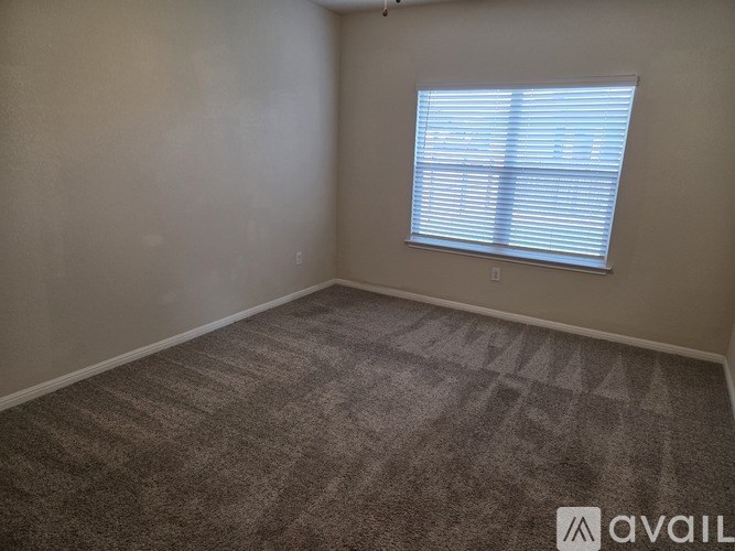 A room with a carpeted floor and a window with blinds.