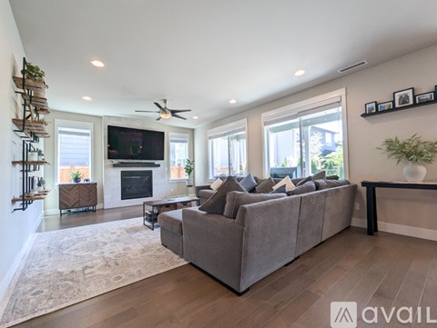 A living room with a grey couch and a fireplace.