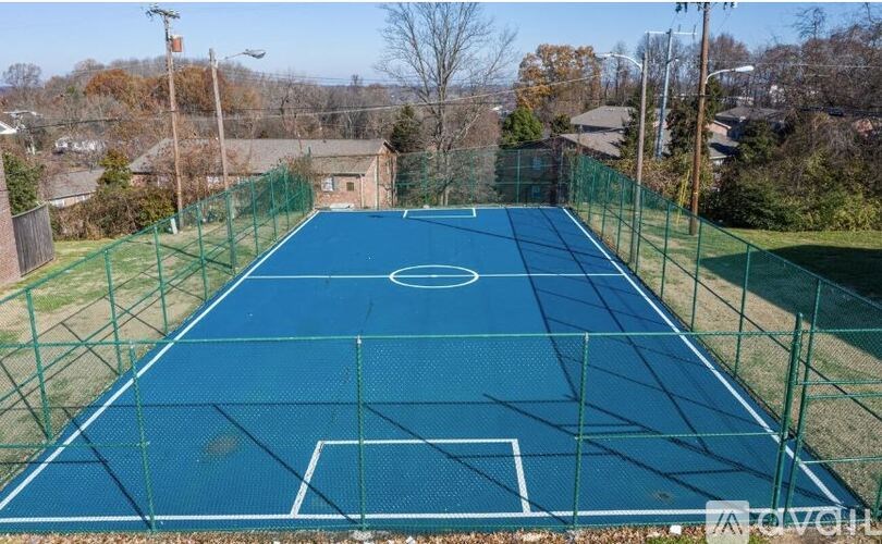 A blue tennis court surrounded by a green fence.