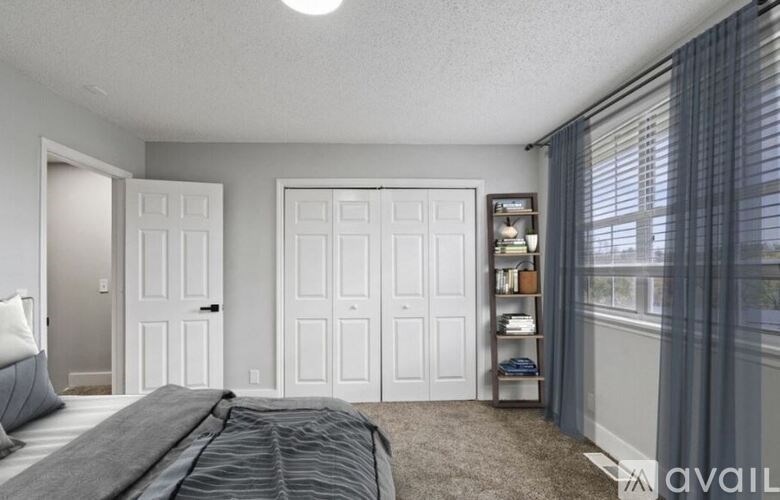 A bedroom with a bed, two doors, and a window with curtains.